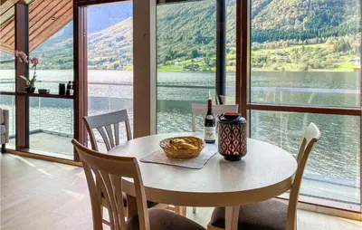 a table with a bottle of wine and a bowl of food on it at 2 Bedroom Cozy Home In Straumgjerde in Riksem
