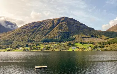 a boat on a lake in front of a mountain at 2 Bedroom Cozy Home In Straumgjerde in Riksem