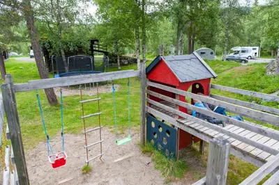 a playground with a toy house and a swing at Groven Camping & Hyttegrend in Åmot