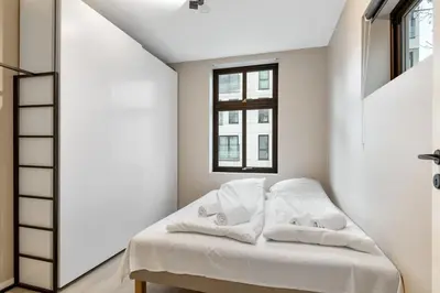 a bedroom with a bed with white sheets and a window at Dinbnb Apartments I New 2021 I Affordable Option in Bergen