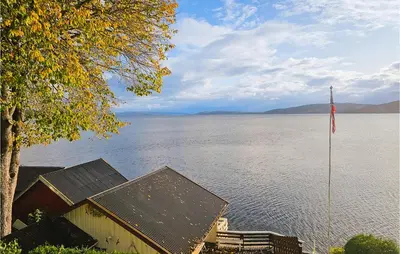 a house next to a large body of water with a flag at 3 Bedroom Lovely Home In Mosvik in Mosvik