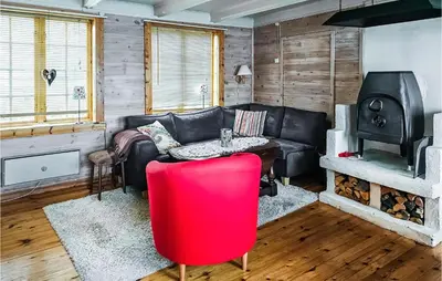 a living room with a black leather couch and a stove at 3 Bedroom Lovely Home In Mosvik in Mosvik
