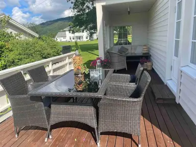 a patio with a table and chairs on a porch at Nakkentunet - familievennlig hus på gårdstun. in Ørskog