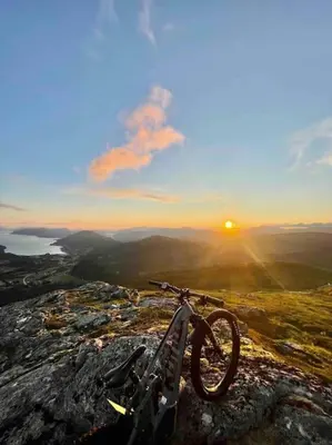 a bike parked on top of a mountain at sunset at Nakkentunet - familievennlig hus på gårdstun. in Ørskog