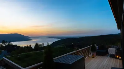 a woman standing on a deck with a view of a lake at Hide Hut - Amazing view 50 min from Oslo in Stange