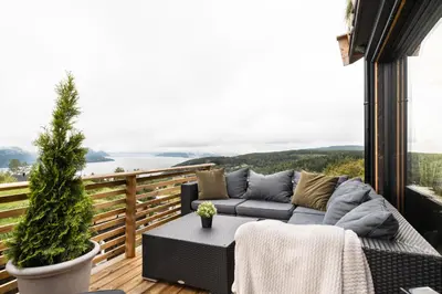 a patio with a couch and a table on a balcony at Hide Hut - Amazing view 50 min from Oslo in Stange
