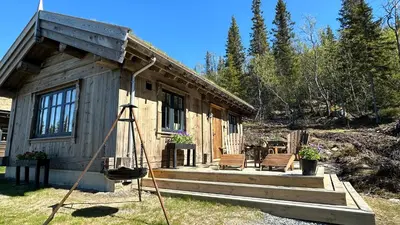 a small wooden cabin with a porch and two benches at Liaplassen Mountain Chalet - Beitostølen in Beitostøl
