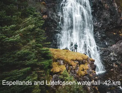 a man standing on a rock in front of a waterfall at Apartment-A near Etne-Odda in Etnesjøen