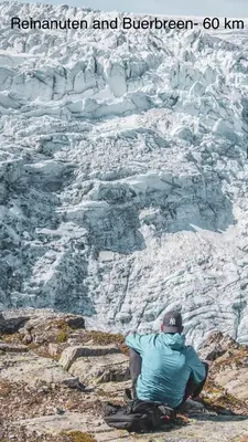 a man sitting on top of a mountain looking at a glacier at Apartment-A near Etne-Odda in Etnesjøen