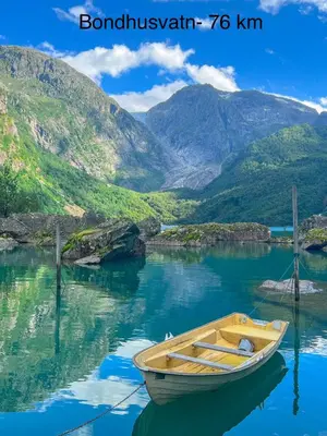 a boat sitting in the water with mountains in the background at Apartment-A near Etne-Odda in Etnesjøen