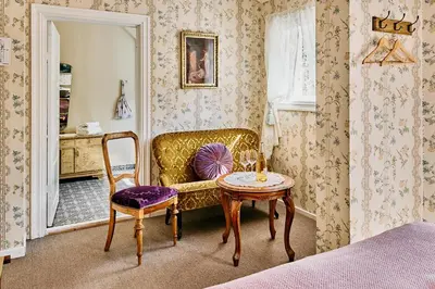 a bedroom with a couch and a table and a chair at Visnes Hotel Stryn in Stryn