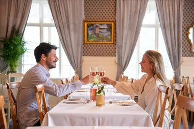 a man and woman sitting at a table with wine glasses at Visnes Hotel Stryn in Stryn