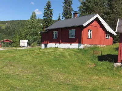 a red barn on a green field with a truck at Åsgardane Gjestegard in Gol