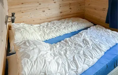 an unmade bed in a room with a wooden wall at Lovely Home In Veggli With Kitchen in Veggli