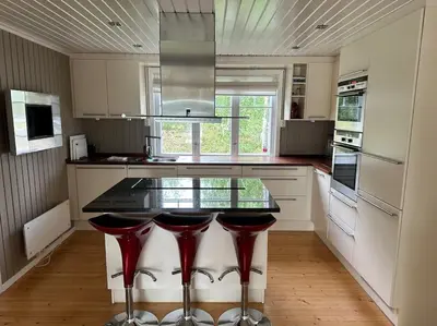 a kitchen with a counter with four red bar stools at Skomakerhuset in Løten