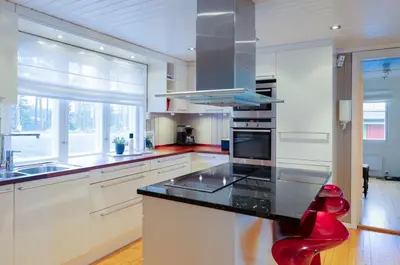 a kitchen with white cabinets and a black counter top at Skomakerhuset in Løten