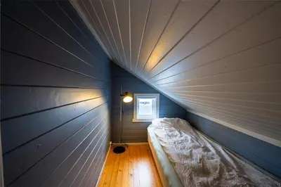 a small room with a bed in a blue wall at Skomakerhuset in Løten