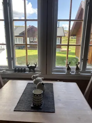 a table with a vase sitting on a table with windows at Osetunet, small and charming cabin at Ustaoset in Ustaoset