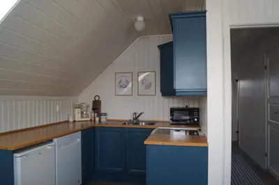 a kitchen with blue cabinets and a counter top at Waterfront Rorbu - By the Beach in Bud
