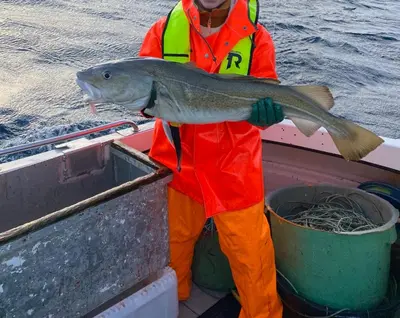 a man holding a fish on a boat at Waterfront Rorbu - By the Beach in Bud