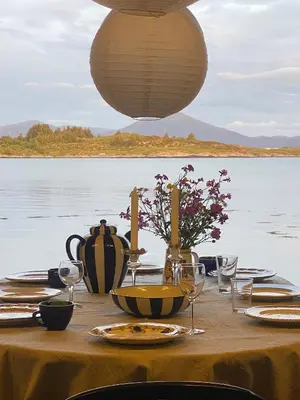 a table with plates and wine glasses and a view of the water at Waterfront Rorbu - By the Beach in Bud