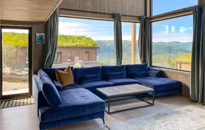 a living room with a blue couch and large windows at 4 Bedroom Nice Home In Tuddal in Tuddal