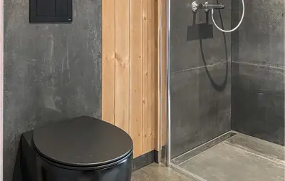 a shower with a black stool next to a toilet at 4 Bedroom Nice Home In Tuddal in Tuddal