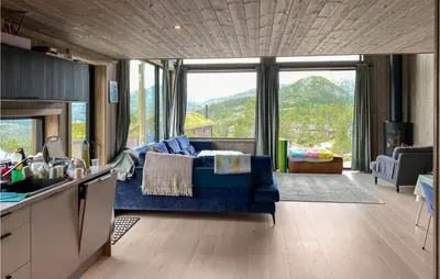 a living room with a blue couch and a large window at 4 Bedroom Nice Home In Tuddal in Tuddal