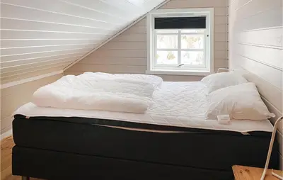 a bed sitting in a room with a window at 4 Bedroom Nice Home In Midsund in Midsund