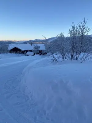a field covered in snow with a barn in the background at Saballie - Cosy cabin - sunny location! in Slåtto