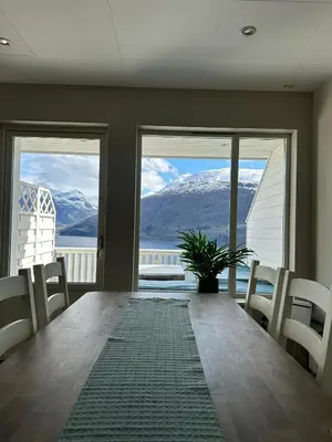 a dining room table with chairs and a view of the mountains at Leilighet med fantastisk utsikt in Stryn