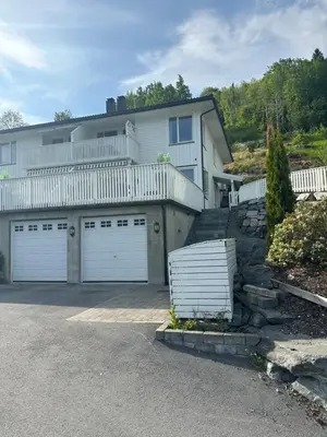 a large white house with two garage doors at Leilighet med fantastisk utsikt in Stryn