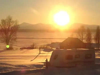 a camper van parked in a field with the sunset at Båtstø Camping in Elga