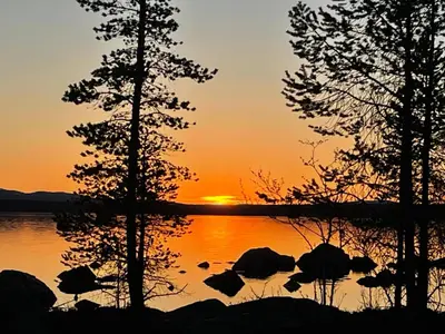 a sunset over a lake with trees and rocks at Båtstø Camping in Elga