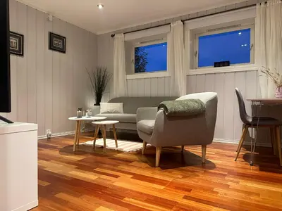 a living room with a couch and a table and two windows at Leilighet for korttidsleie in Otta