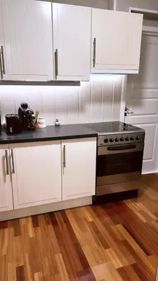a kitchen with white cabinets and a black stove at Leilighet for korttidsleie in Otta