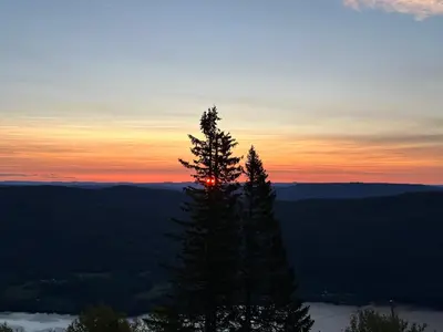 a sunset in the mountains with a tree in the foreground at Ny leilighet på Norefjell - ski in/out in Noresund