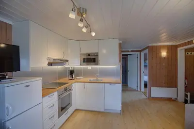 a kitchen with white cabinets and a television in it at Kvetos naturopplevelser in Beitostøl