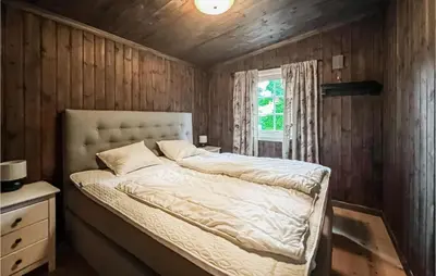 a bed in a room with wooden walls and a window at Beautiful Home In Sjusjøen With Kitchen in Sjusjøen