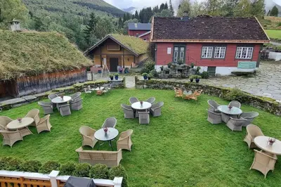 an outdoor patio with tables and chairs in front of a building at Apartment, Rekkedal Gjestegard - Sæbø in Ørsta
