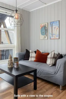 a living room with a couch with a view to the slopes at Hafjell Alpinlandsby Apt 88 in Hafjell