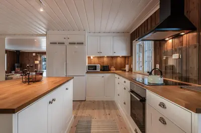 a kitchen with white cabinets and a wooden ceiling at Sunny and beautiful cabin in Geilo in Geilo
