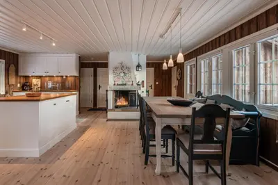 a kitchen and dining room with a table and a fireplace at Sunny and beautiful cabin in Geilo in Geilo