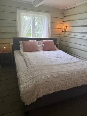 a bedroom with a bed with pink pillows and a window at Draget gård, historisk våningshus ved sjøen, rett utenfor Molde in Molde
