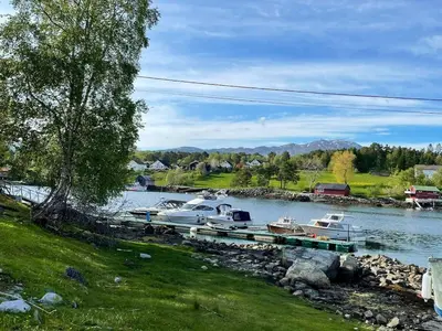 a group of boats docked at a dock on a river at Draget gård, historisk våningshus ved sjøen, rett utenfor Molde in Molde