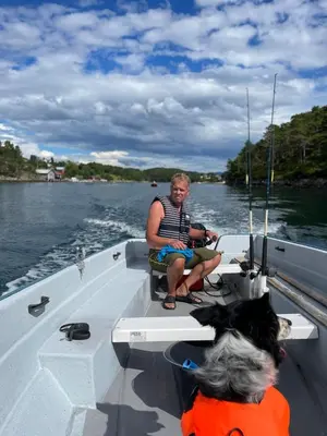 a man sitting on the back of a boat on the water at Draget gård, historisk våningshus ved sjøen, rett utenfor Molde in Molde