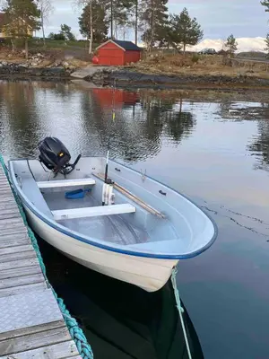 a white boat parked next to a dock at Draget gård, historisk våningshus ved sjøen, rett utenfor Molde in Molde