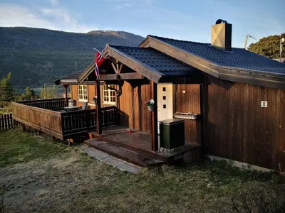 a large wooden cabin with a porch and a flag at Feriebolig i Garmo in Lom
