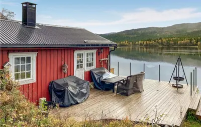 a red house on a dock next to a body of water at Nice Home In Follafoss With Lake View in Sela