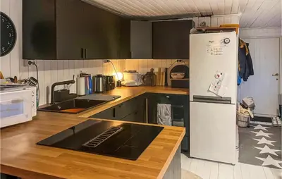 a kitchen with black cabinets and a white refrigerator at Nice Home In Follafoss With Lake View in Sela